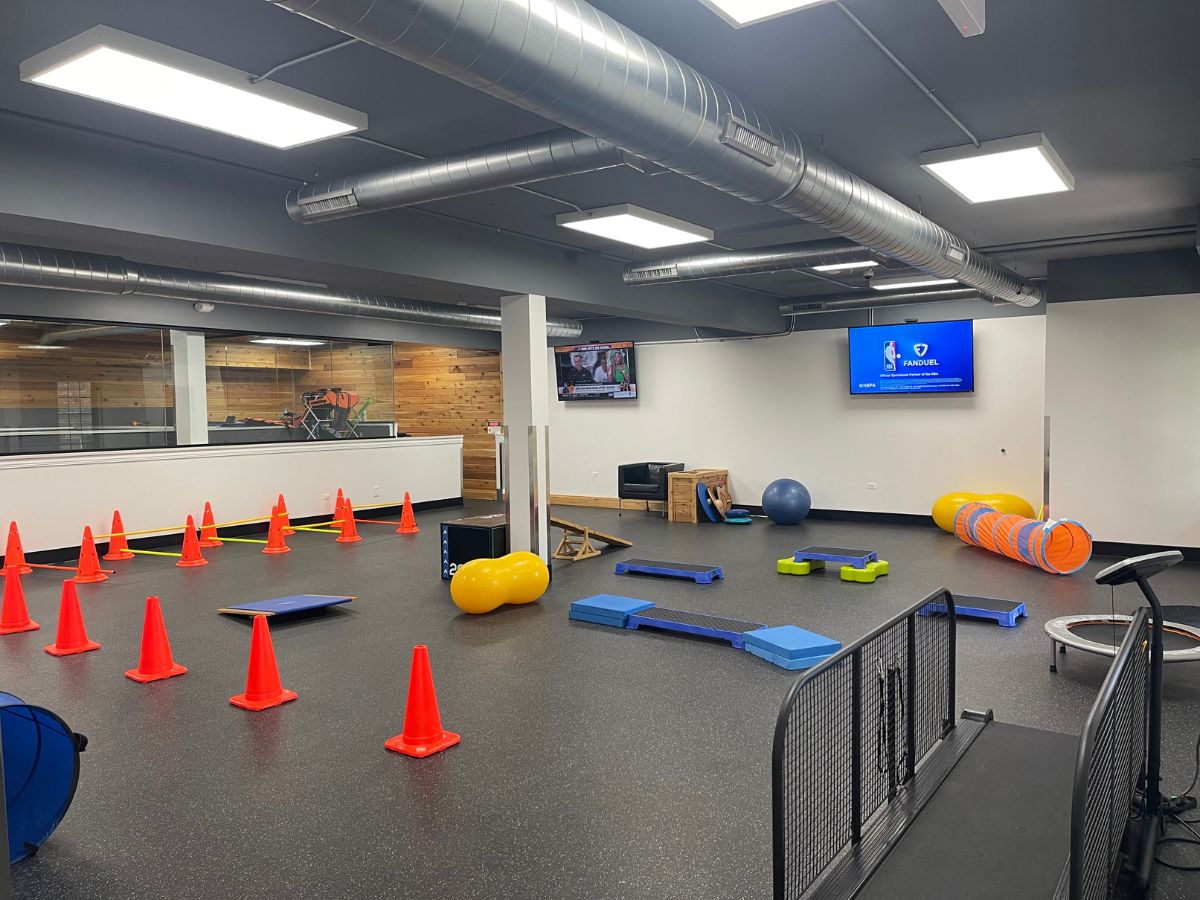 Indoor gym with exercise equipment and cones.